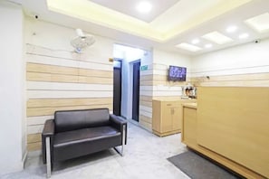 A reception area with a sofa, a wooden cabinet, and a television on the wall. - FabHotel Premium Stay Dasrathpuri (New Delhi)