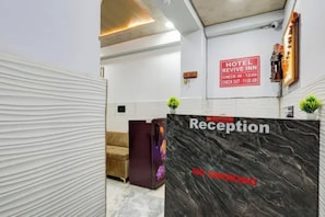 A reception desk with a 'No Smoking' sign and a 'Hotel Revive Inn' sign indicating check-in and check-out times. - FabHotel Premium Stay Dabri (New Delhi)