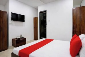Habitación de hotel con una cama, televisor montado en la pared, armario y una mesita con hervidor.