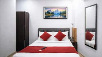 A hotel room with a bed, a painting, a mirror, and a wardrobe.