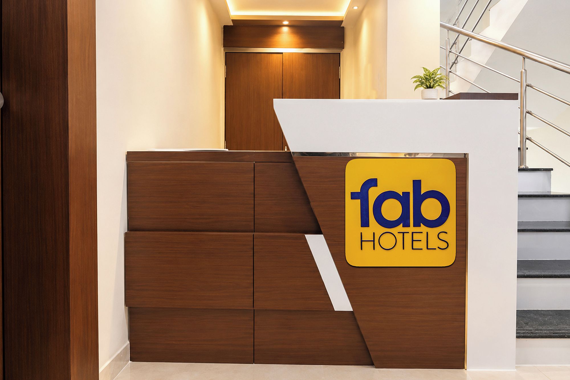 A reception desk with a 'fab hotels' sign, a staircase, and a plant.