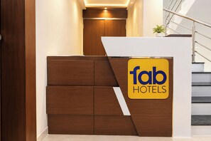 A reception desk with a 'fab hotels' sign, a staircase, and a plant.