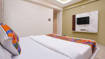 A hotel room with a bed, a TV mounted on the wall, and a small table.