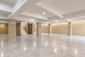 A spacious indoor area with a central staircase, columns, and a plain wall. - FabHotel Royal Inn Regency (Pune)