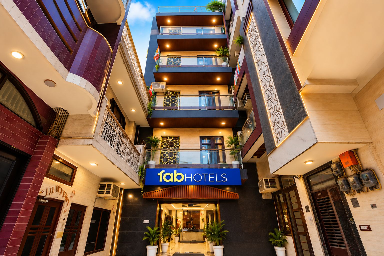 A multi-story hotel with a prominent 'fabHOTELS' sign, outdoor seating, and a modern architectural design.
