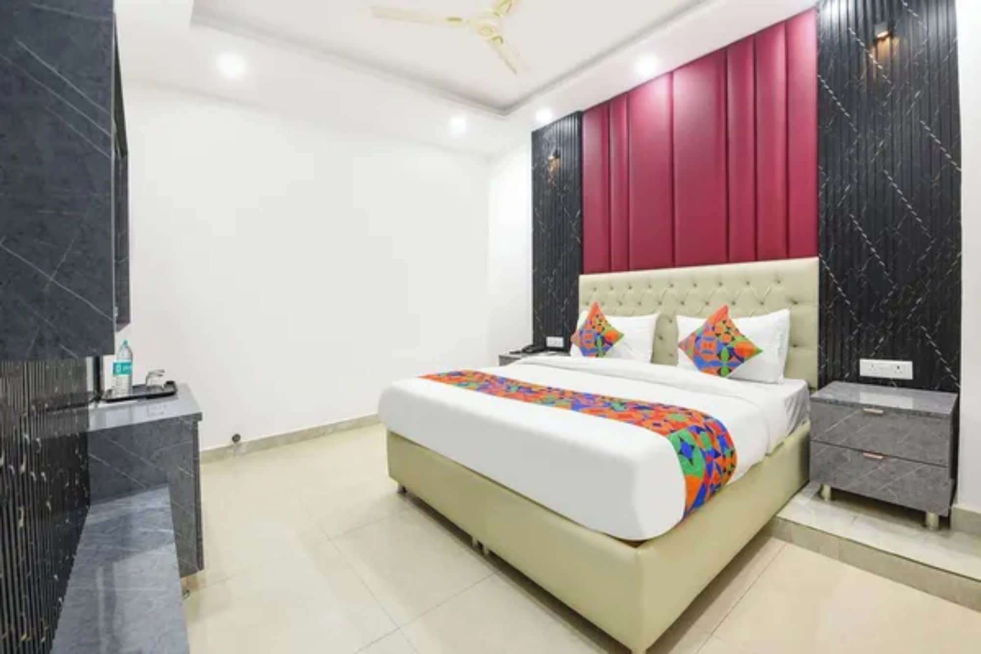 A hotel room with a large bed, a bedside table, a nightstand, and a modern ceiling fan.
