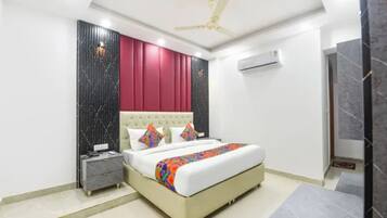 Une chambre à coucher moderne, équipée d’un lit, d’une table de chevet, d’un ventilateur de plafond et d’un appareil de climatisation.