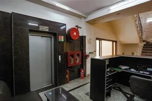 Una oficina con una puerta cerrada, un extintor y una escalera.