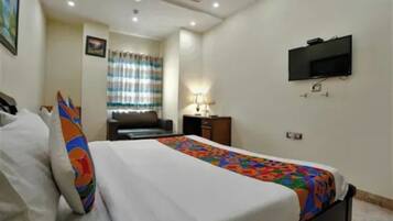 Una habitación de hotel con una cama, un televisor montado en la pared y un escritorio con una lámpara.