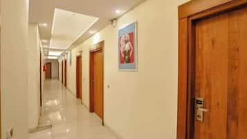 Un pasillo de hotel con puertas de madera, un cartel en la pared y un suelo de baldosas.