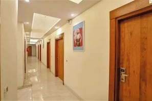 Un pasillo de hotel con puertas de madera, un cartel en la pared y un suelo de baldosas.