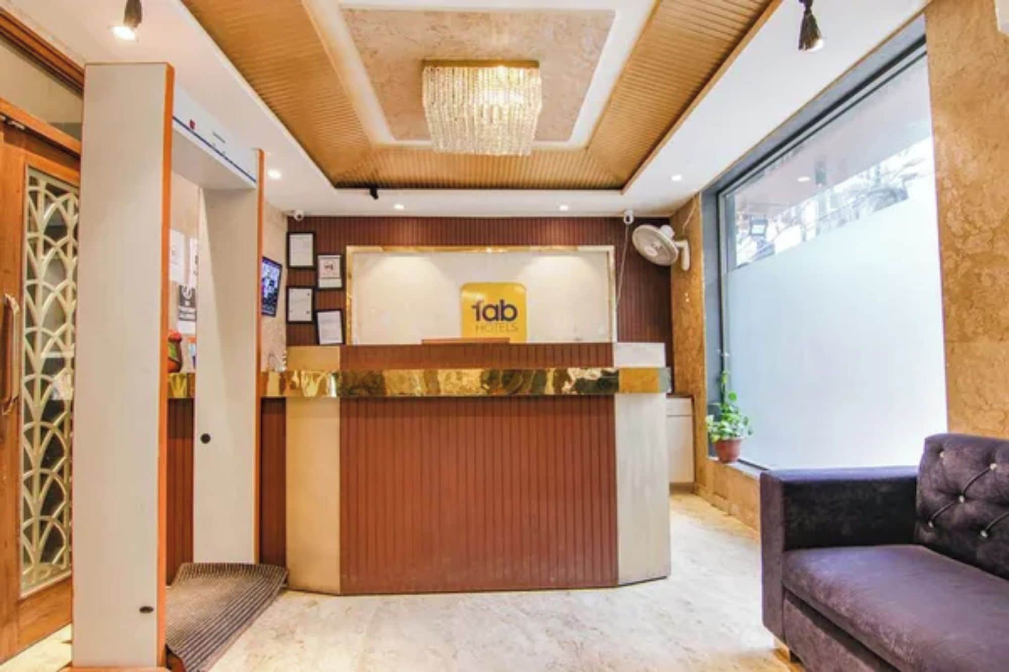 A hotel reception desk with a chandelier, a plush sofa, and framed certificates on the wall.