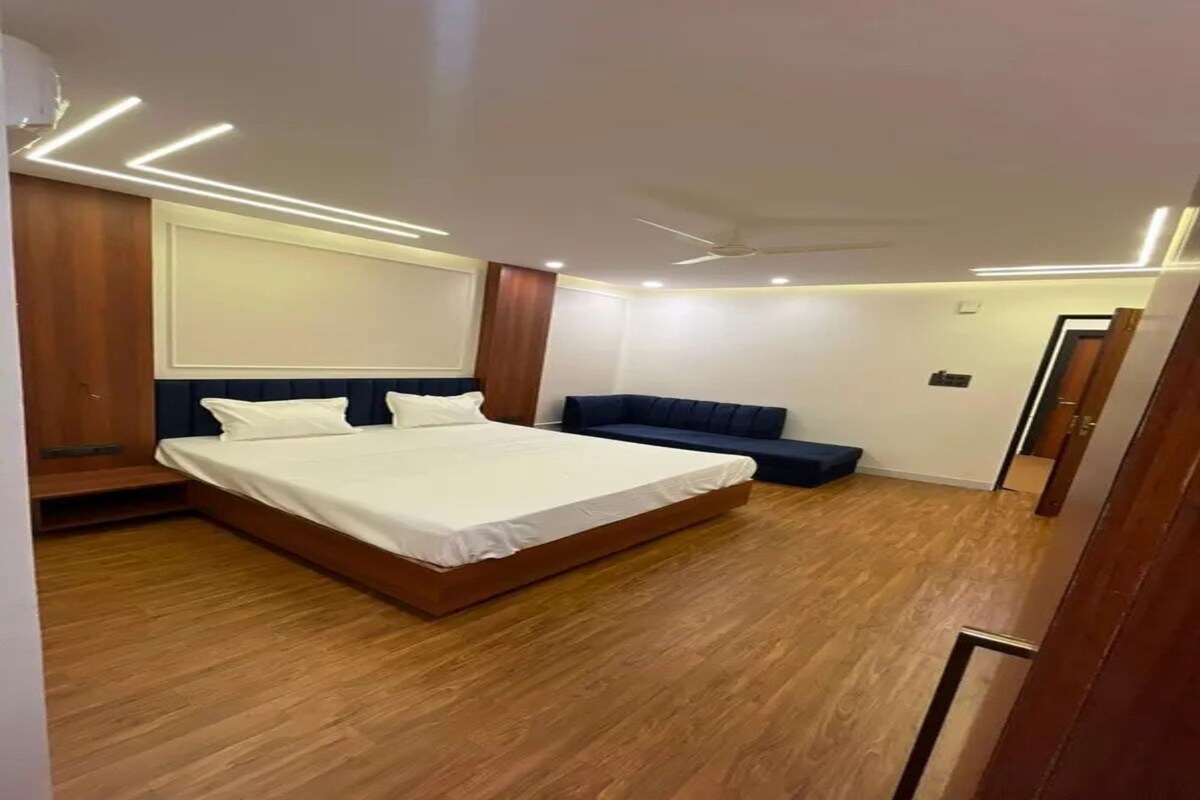 Una habitación de hotel con una cama grande, una zona de estar y un ventilador de techo.