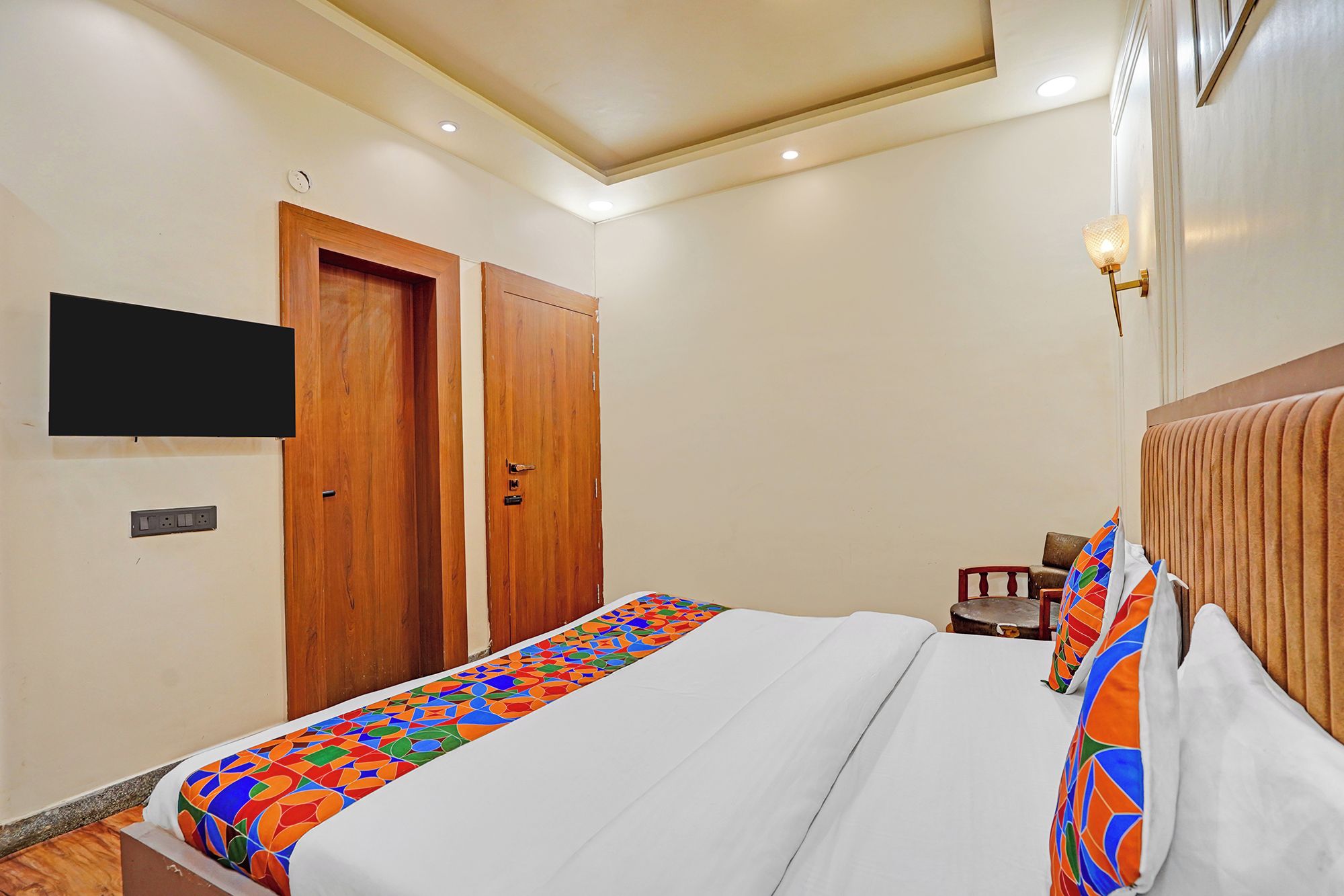 Una camera d'albergo con un letto, una televisione appesa al muro e una porta in legno.