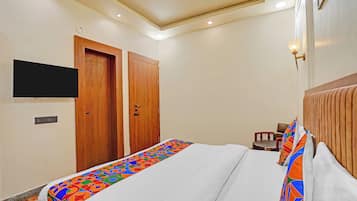Una camera d'albergo con un letto, una televisione appesa al muro e una porta in legno.