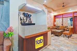 A hotel reception area with a modern design, including a reception desk, seating area, and decorative elements. - FabHotel Amantran (Kanpur)
