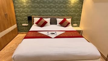 Een net opgemaakt bed met een wit-rode sprei, een houten hoofdbord en een groene, bewerkte muur.
