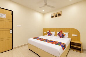 Une chambre d’hôtel avec un lit, une table de chevet, un ventilateur de plafond et une porte avec une pancarte.