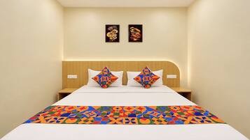 A hotel room with a bed, two pillows, a headboard, and two wall-mounted artworks.