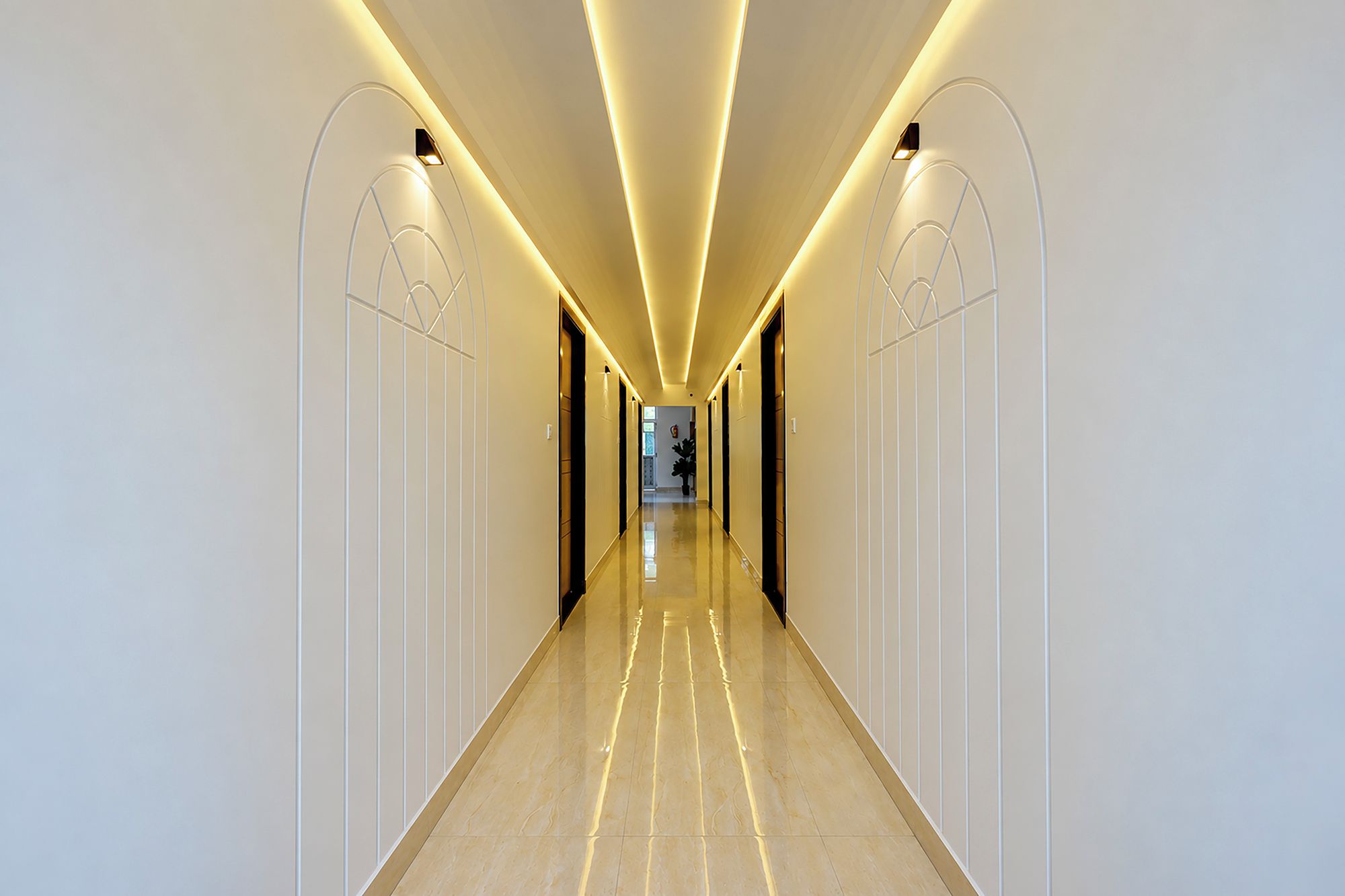 A modern hotel corridor with a long, straight path, light-colored walls, and a polished floor.