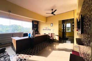 A reception area with a desk, chairs, a ceiling fan, and a wall sign reading 'Nammo Stay'. - FabHotel K Hotels (Bangalore)