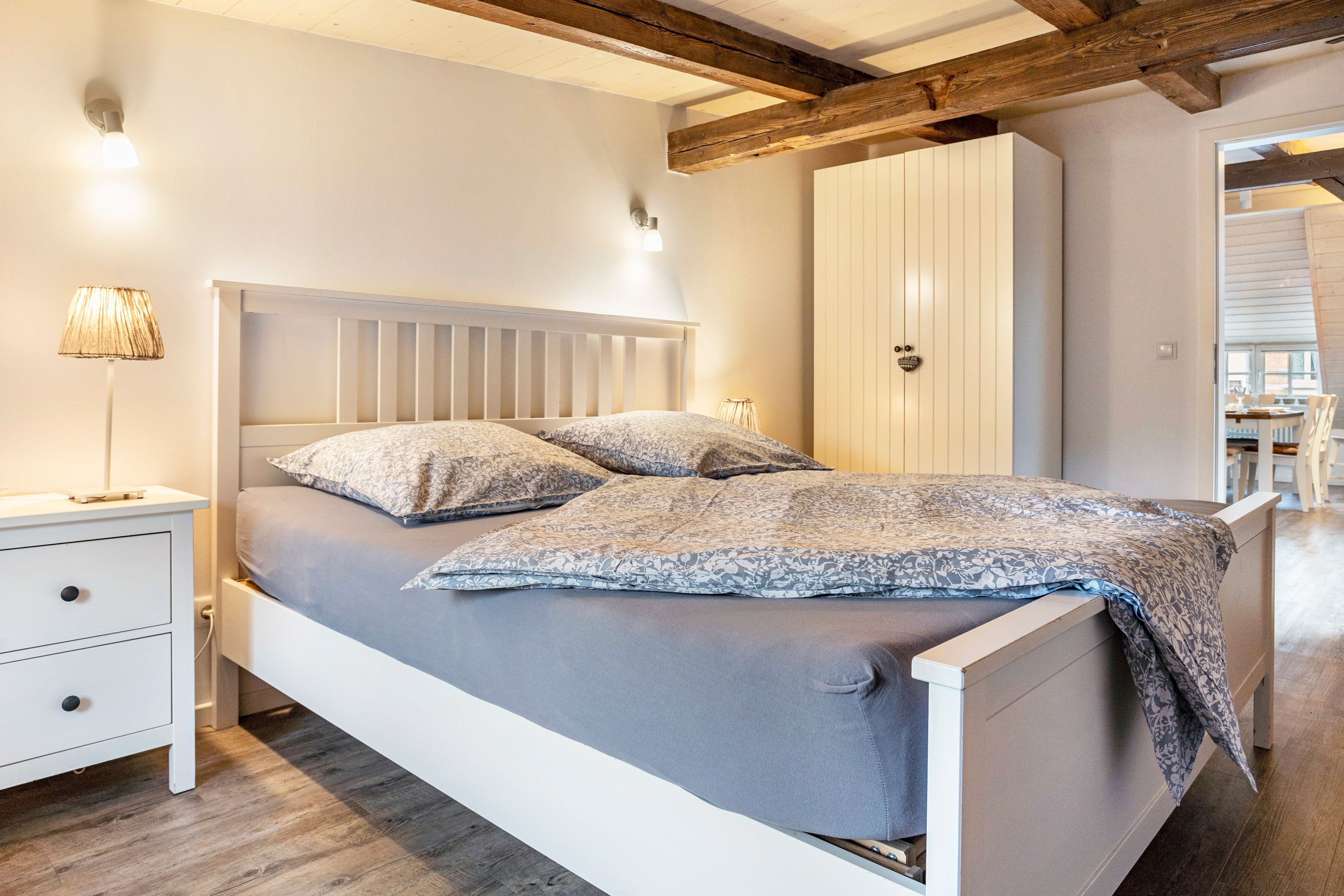 Une chambre à coucher avec un lit, des tables de chevet, une armoire et une lampe.