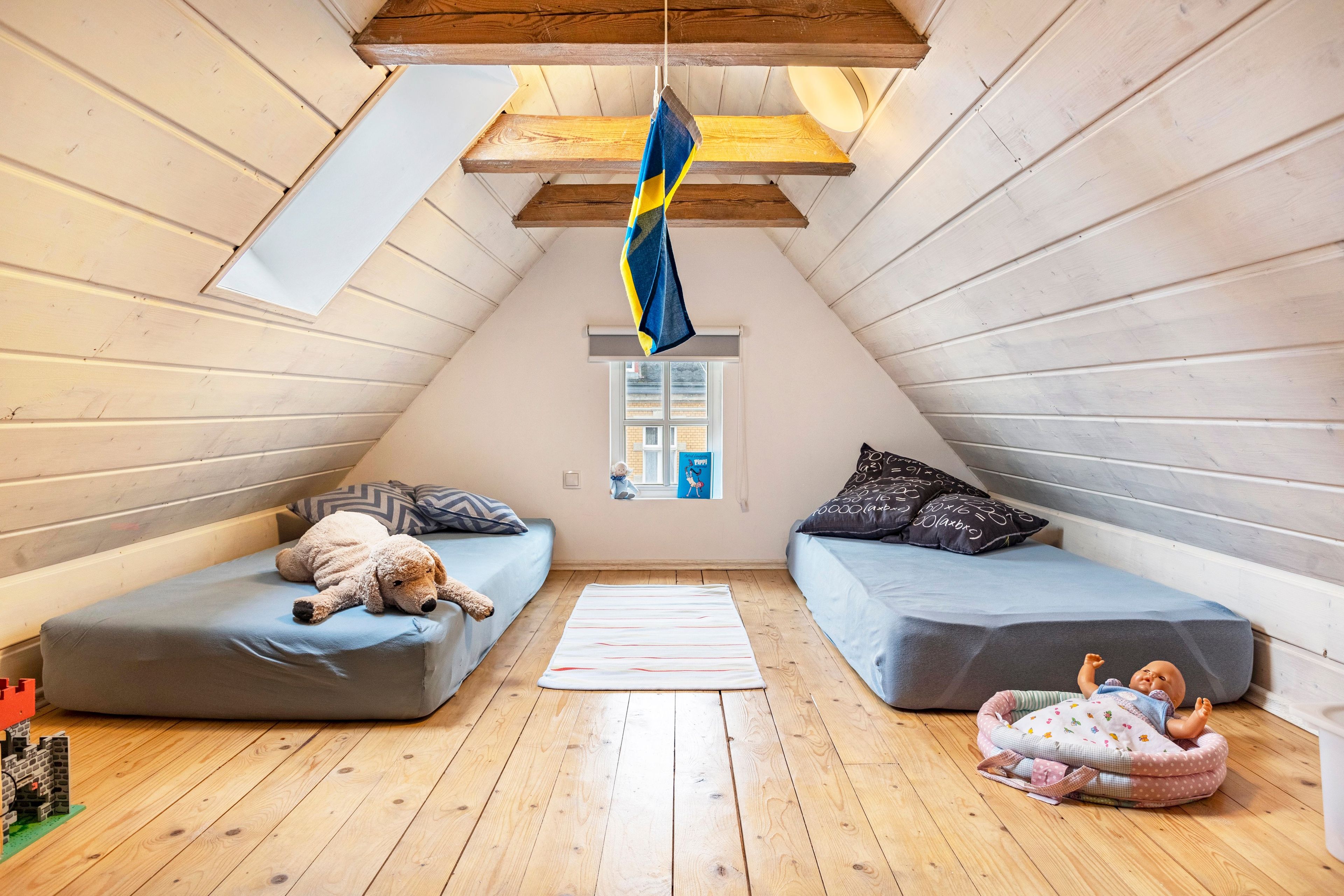Ein gemütliches Schlafzimmer im Dachgeschoss mit zwei Etagenbetten, Holzboden und einem Fenster mit Blick.