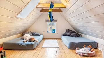 Ein gemütliches Schlafzimmer im Dachgeschoss mit zwei Etagenbetten, Holzboden und einem Fenster mit Blick.