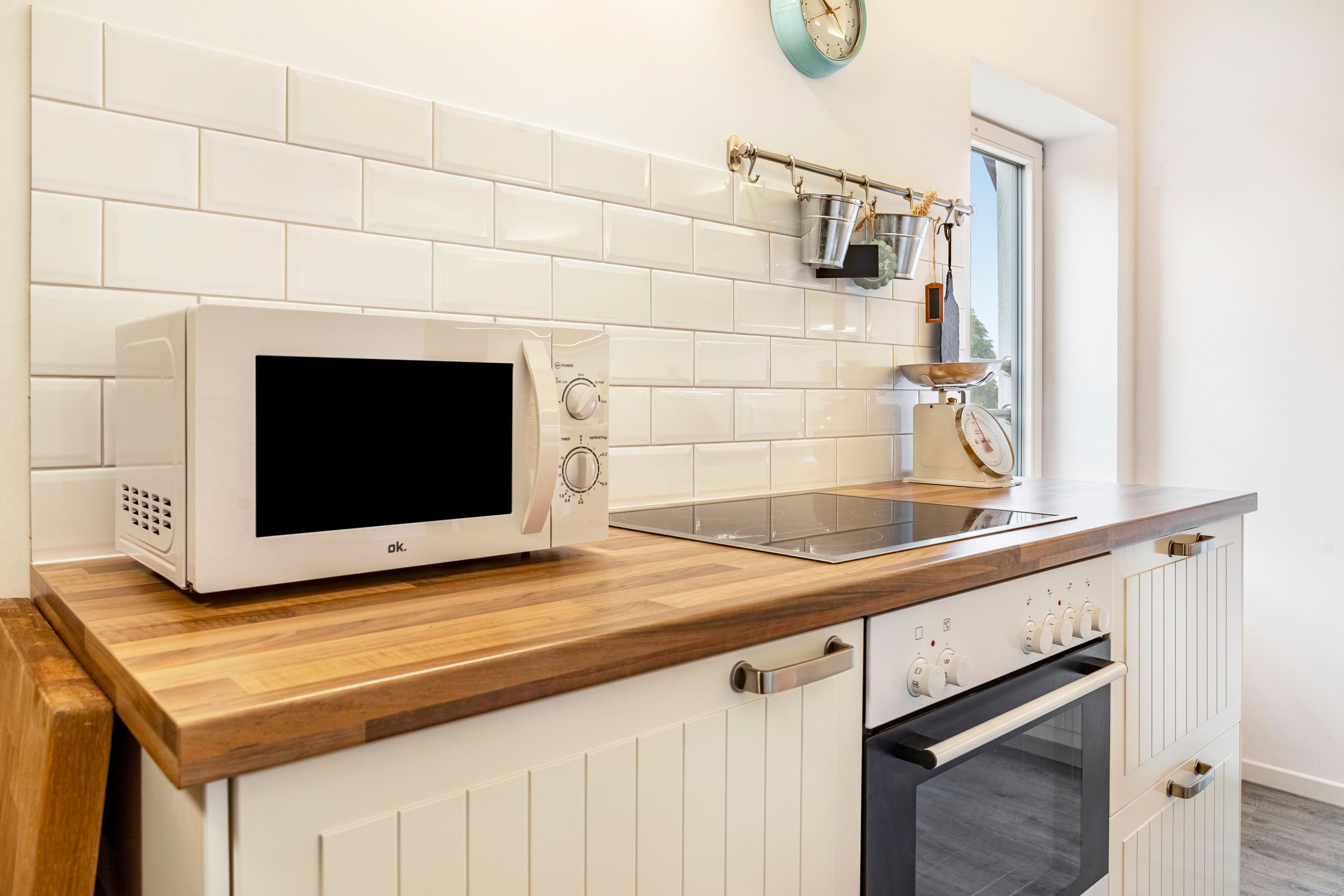 Une cuisine avec des meubles blancs, un four à micro-ondes, une cuisinière et une fenêtre donnant sur un beau paysage.