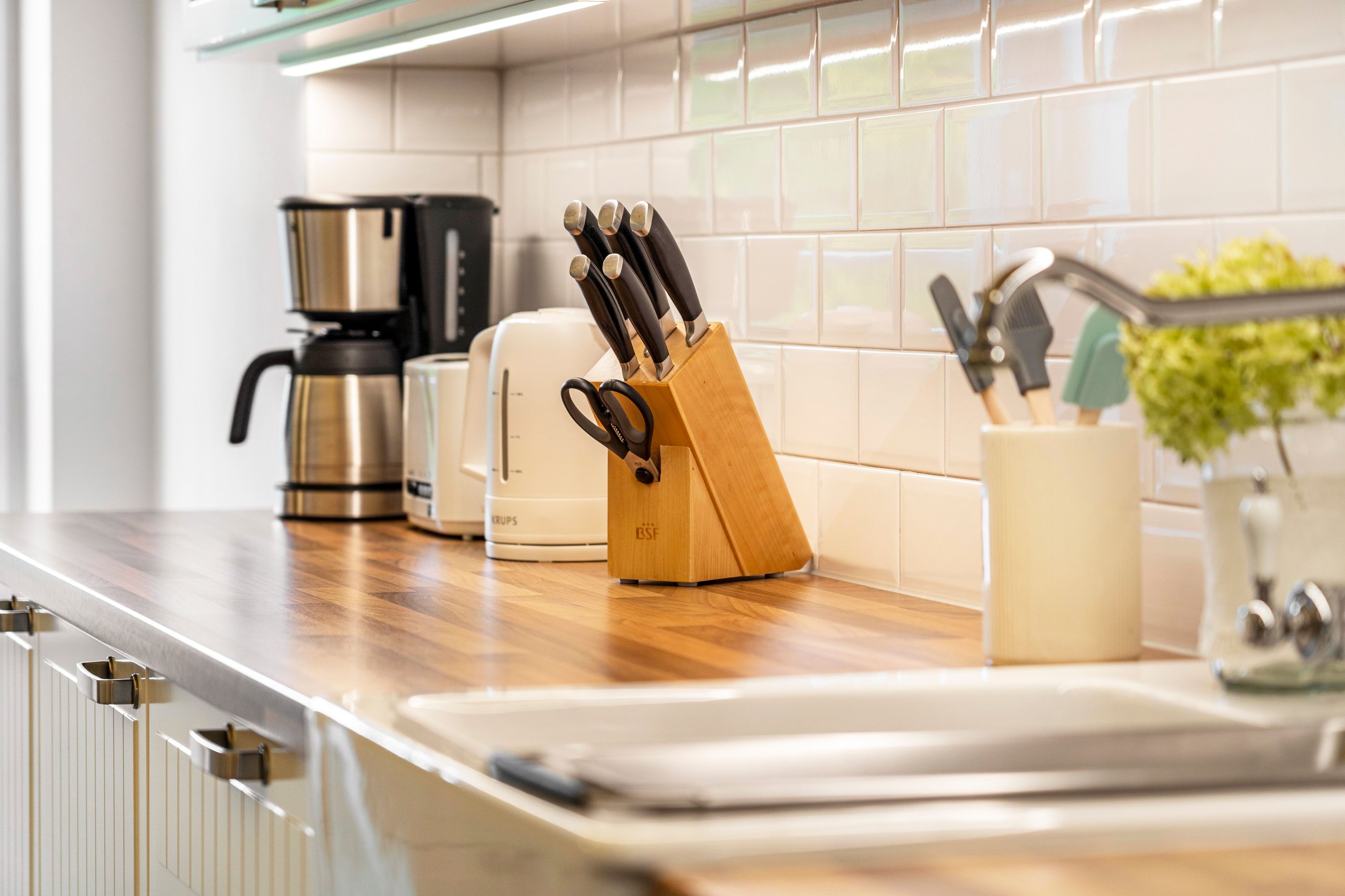 Una cocina con cafetera, tostadora y un bloque de cuchillos sobre la encimera.