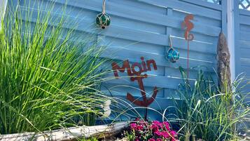 A building with a blue exterior, a wooden fence, and decorative elements including a seahorse and a hanging ornament.