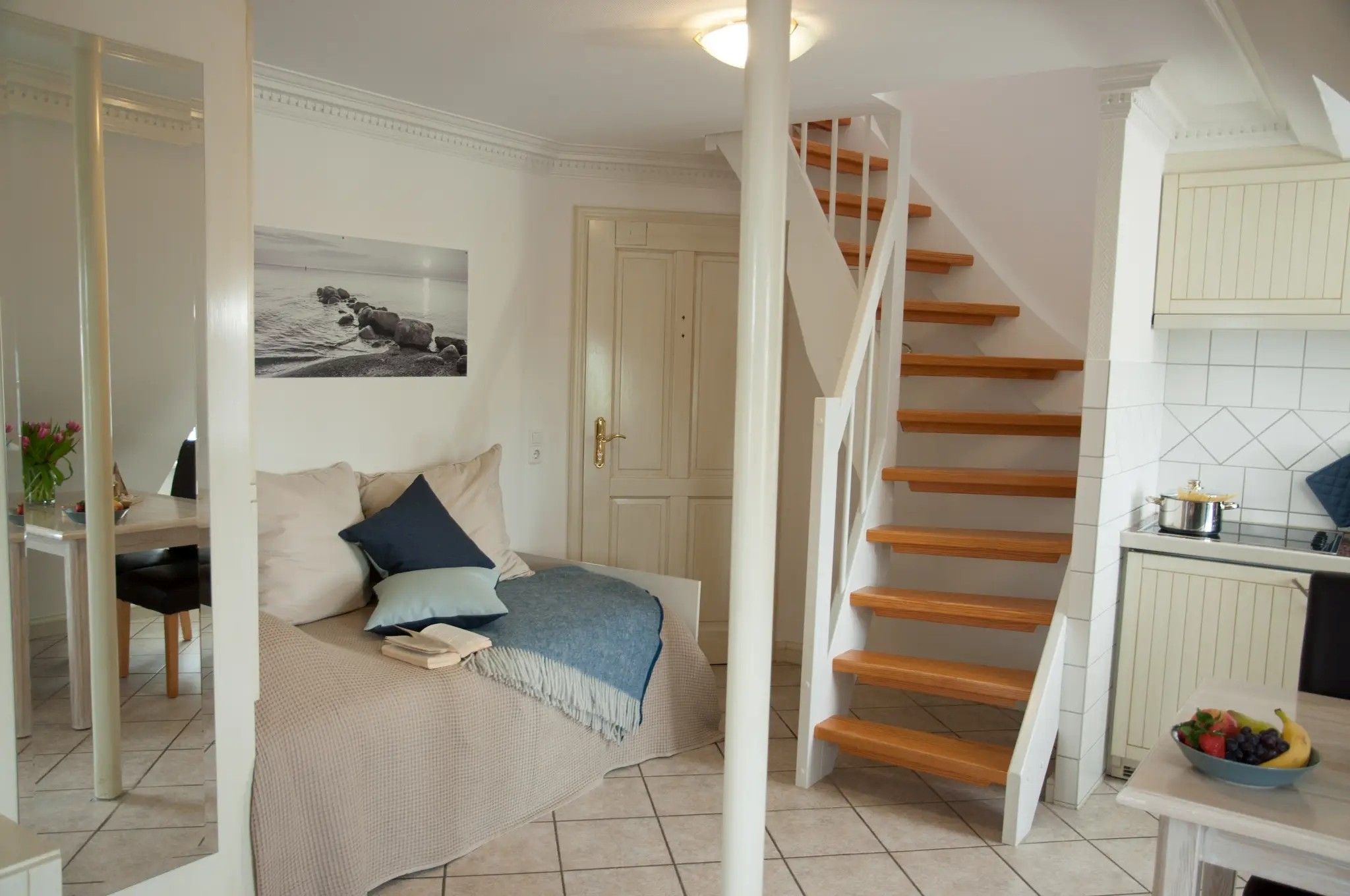 A bedroom with a bed, a bedside table, and a nightstand. There is a staircase leading to an upper floor.