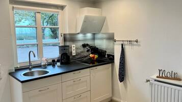 A modern kitchen with a built-in stove, a sink, and a window overlooking a parking area.