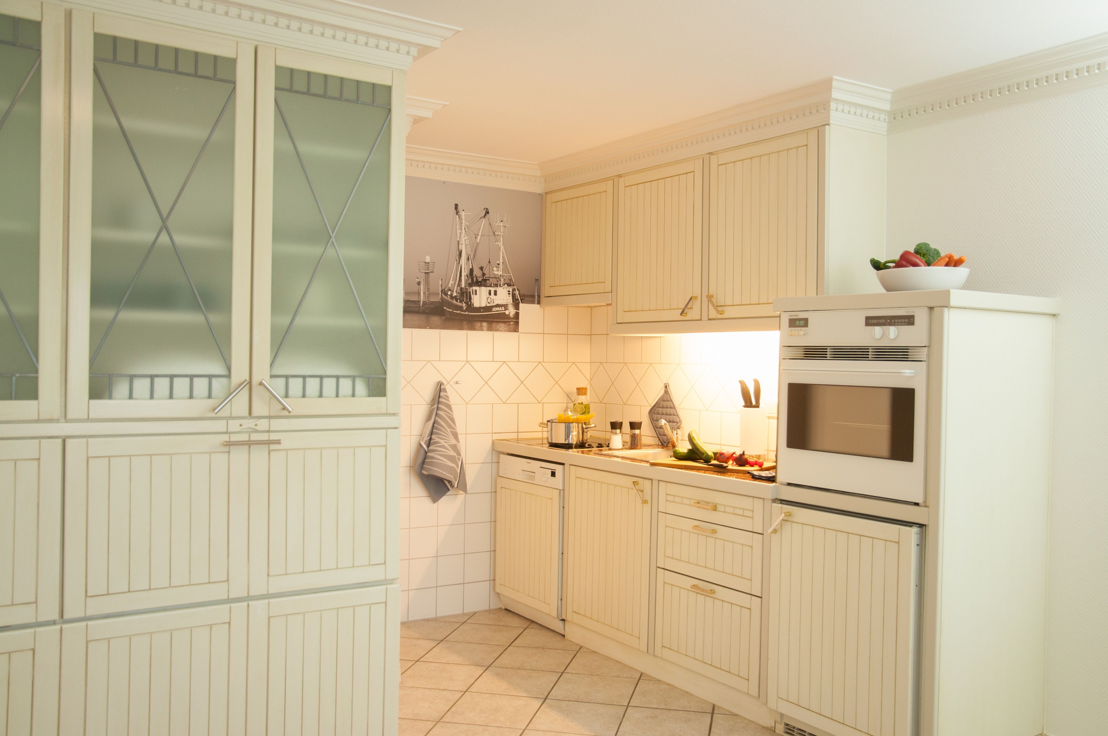 A kitchen with white cabinetry, a tiled backsplash, a stove, and a window with blinds.