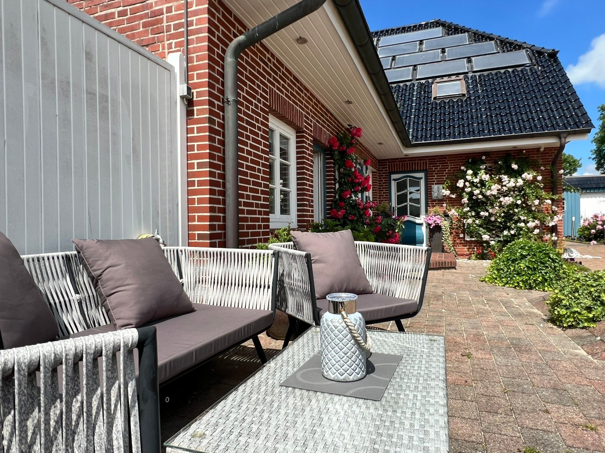 Et udendørs opholdsområde med sofa og stole, et lille bord og en dekorativ vase.