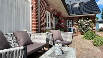 Et udendørs opholdsområde med sofa og stole, et lille bord og en dekorativ vase.