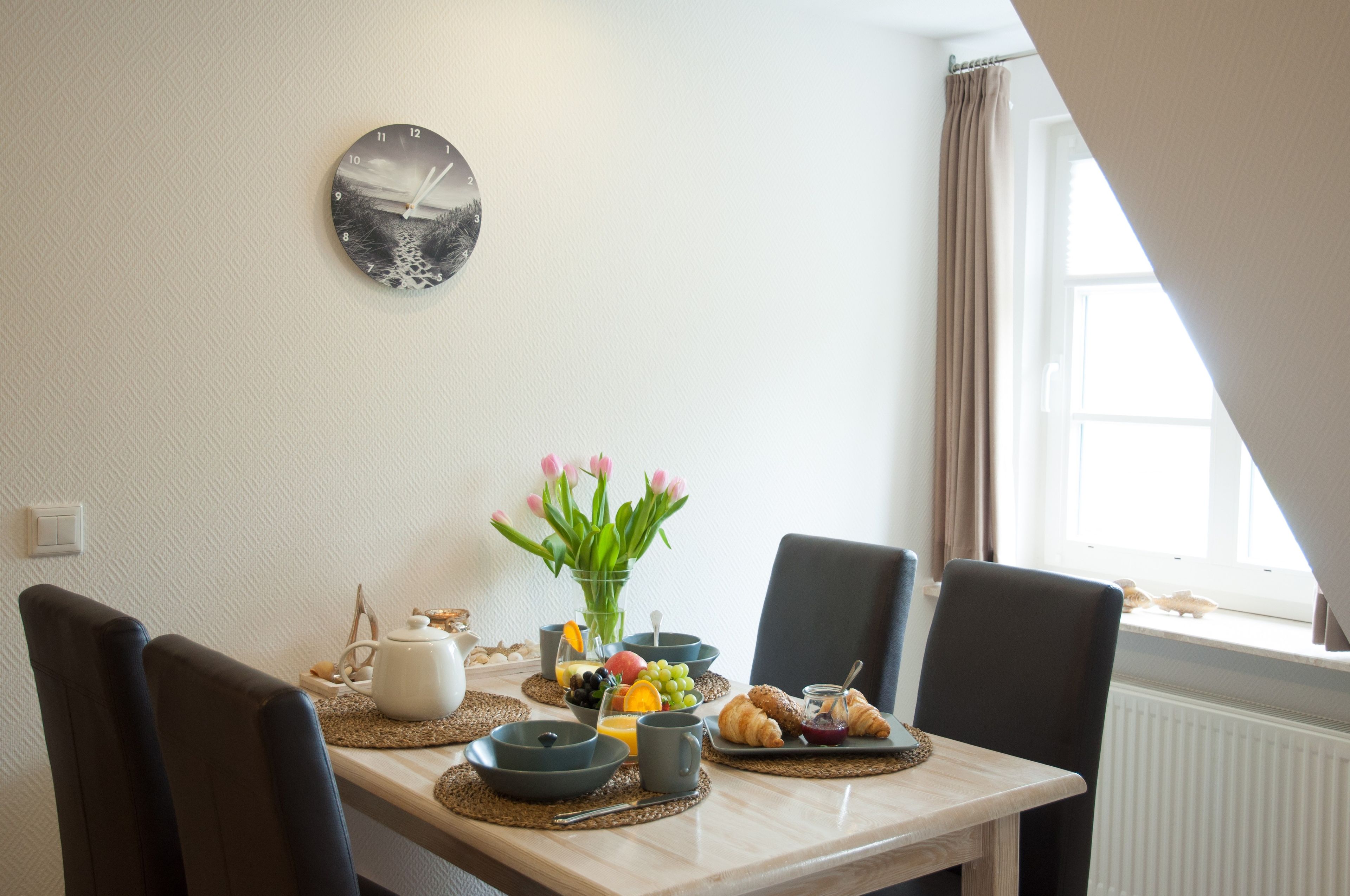 Une table de petit-déjeuner avec des croissants, des fruits et un vase de fleurs.