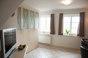 Une cuisine équipée d’un four encastré, d’une fenêtre avec des rideaux et d’un radiateur.
