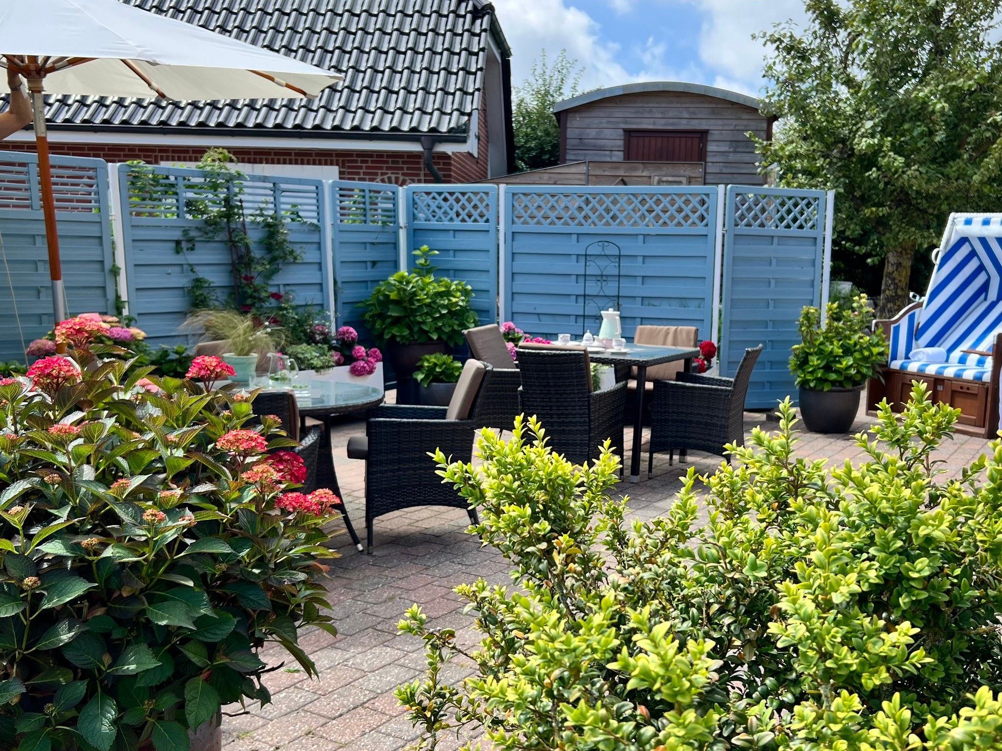 Een terras met tuinmeubilair, een tafel en stoelen.
