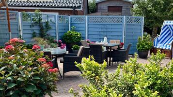 Een terras met tuinmeubilair, een tafel en stoelen.