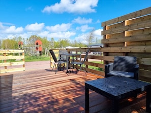 Eine Terrasse im Freien mit Tisch und Stühlen, einer Bank und einem Holzzaun.