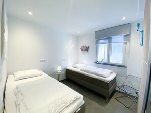 A bedroom with a bed, a bedside table, a lamp, a window, and a chair. - Zo10 Holiday Home Zoutelande (Zoutelande)