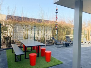 An outdoor patio with a table, benches, and red stools. - Zo10 Holiday Home Zoutelande (Zoutelande)