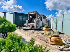 En have med grillplads, en stor plantekasse og et hegn.