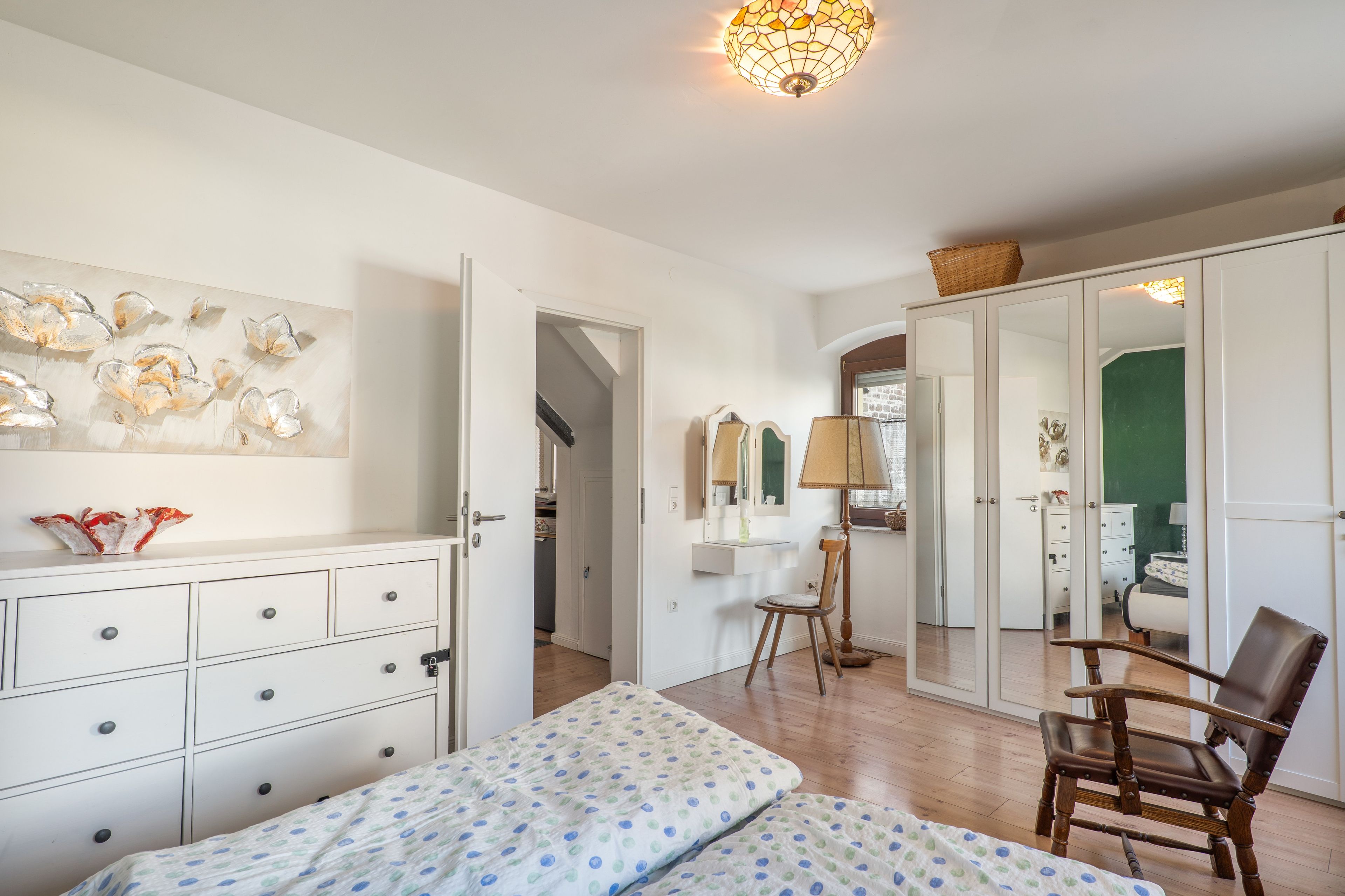 A bedroom with a bed, a dresser, a chair, and a wardrobe.