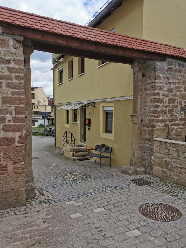 Una calle adoquinada con un edificio de techo de tejas rojas y paredes de piedra.