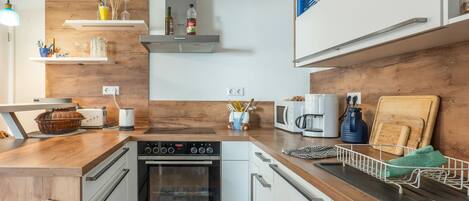 A modern kitchen with white cabinetry, a built-in oven, and a coffee maker.