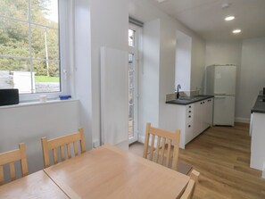 A compact kitchen with a dining area, a refrigerator, and a window with a view of greenery. - 8 Douglas Place (Isle of Arran)