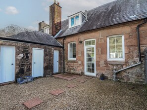 A stone building with a gravel driveway and a small garden area. - 8 Douglas Place (Isle of Arran)