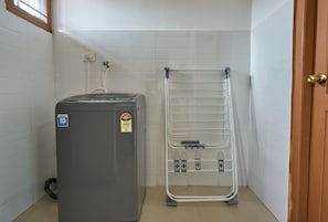 Habitación pequeña con calentador de agua, un tendedero metálico y una puerta.